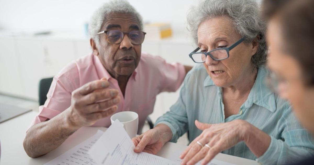 Older couple reviewing insurance paperwork with an advisor at a bright office table