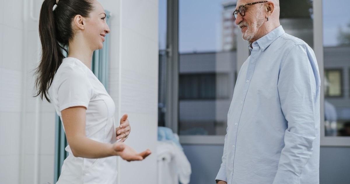 Smiling clinician chatting face to face with an older man during a friendly consultation