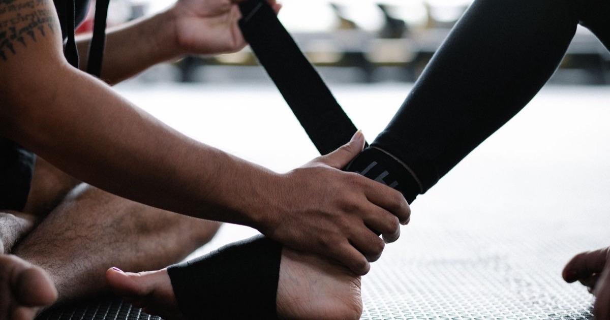 Hands wrapping a supportive elastic bandage around a person's ankle
