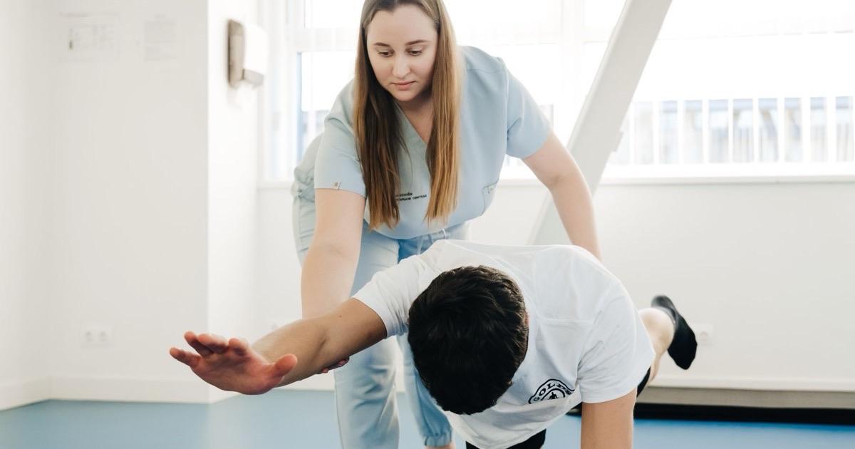 Physical therapist spotting a patient practicing a balance exercise on hands and knees